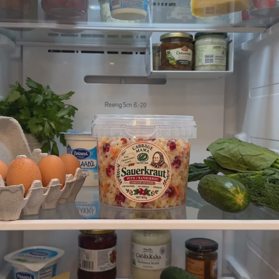 Cabbage Mama sauerkraut jar in an open fridge with fresh vegetables and eggs